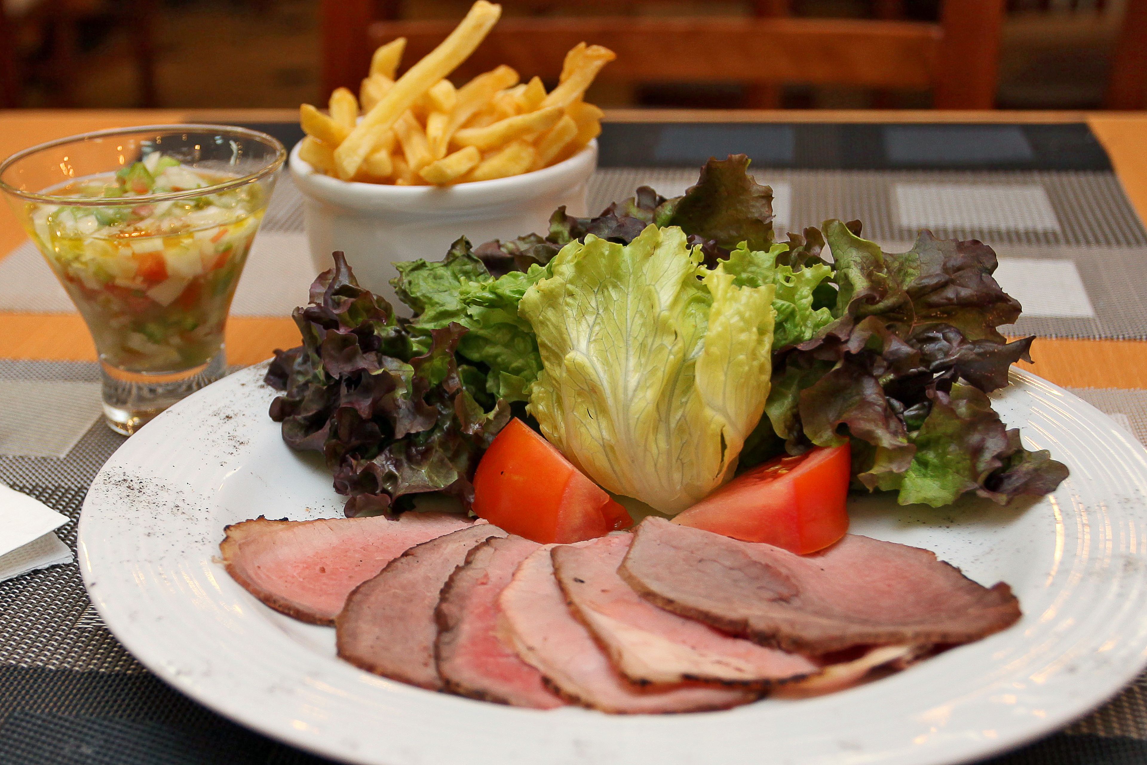 A plate with sliced meat, vegetables, and a side of fries.