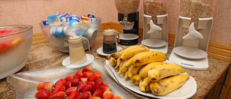 Un buffet de petit-déjeuner proposant divers fruits, une machine à café et un mixeur.