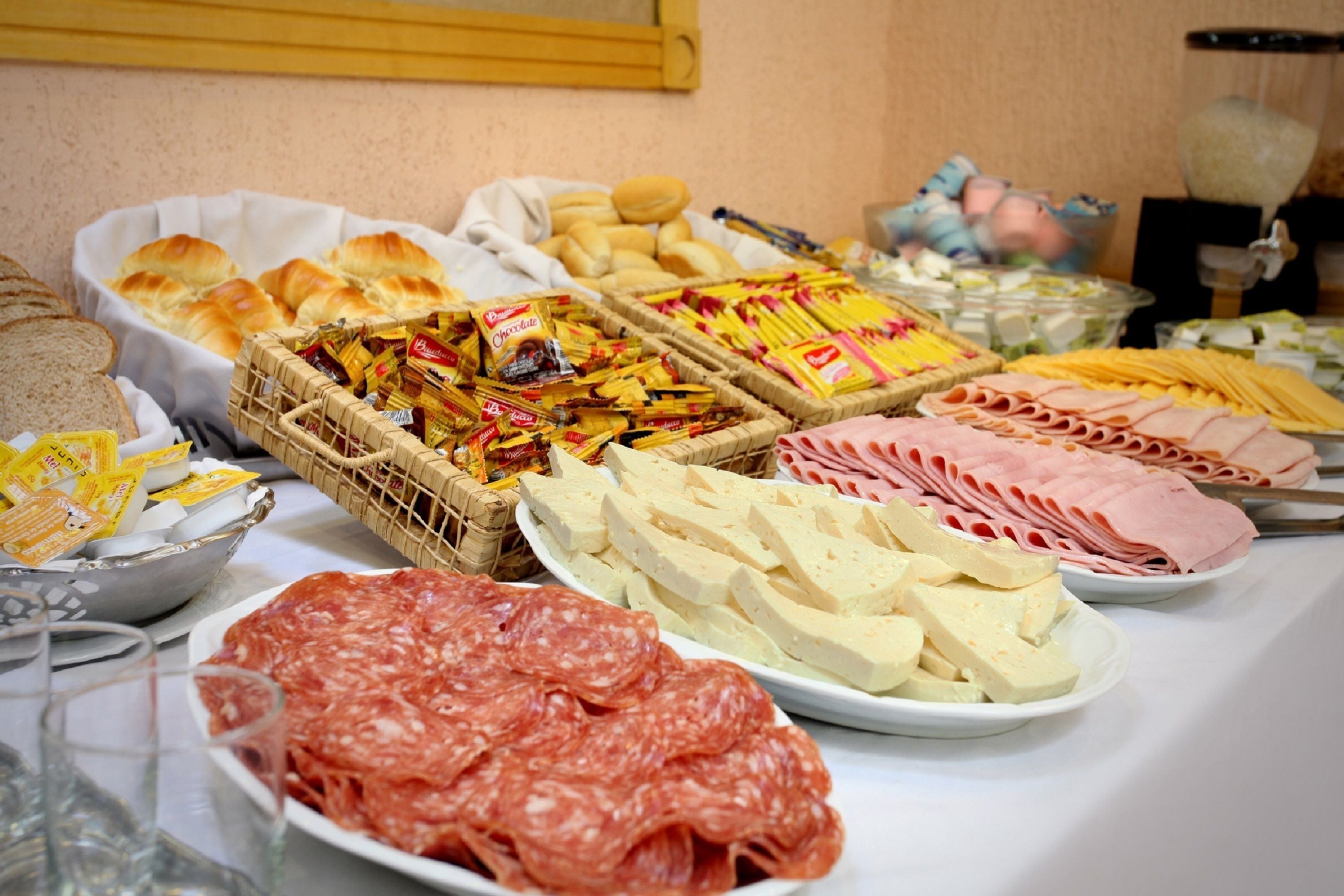 A buffet table with various food items including bread, pastries, cheese, and meats.