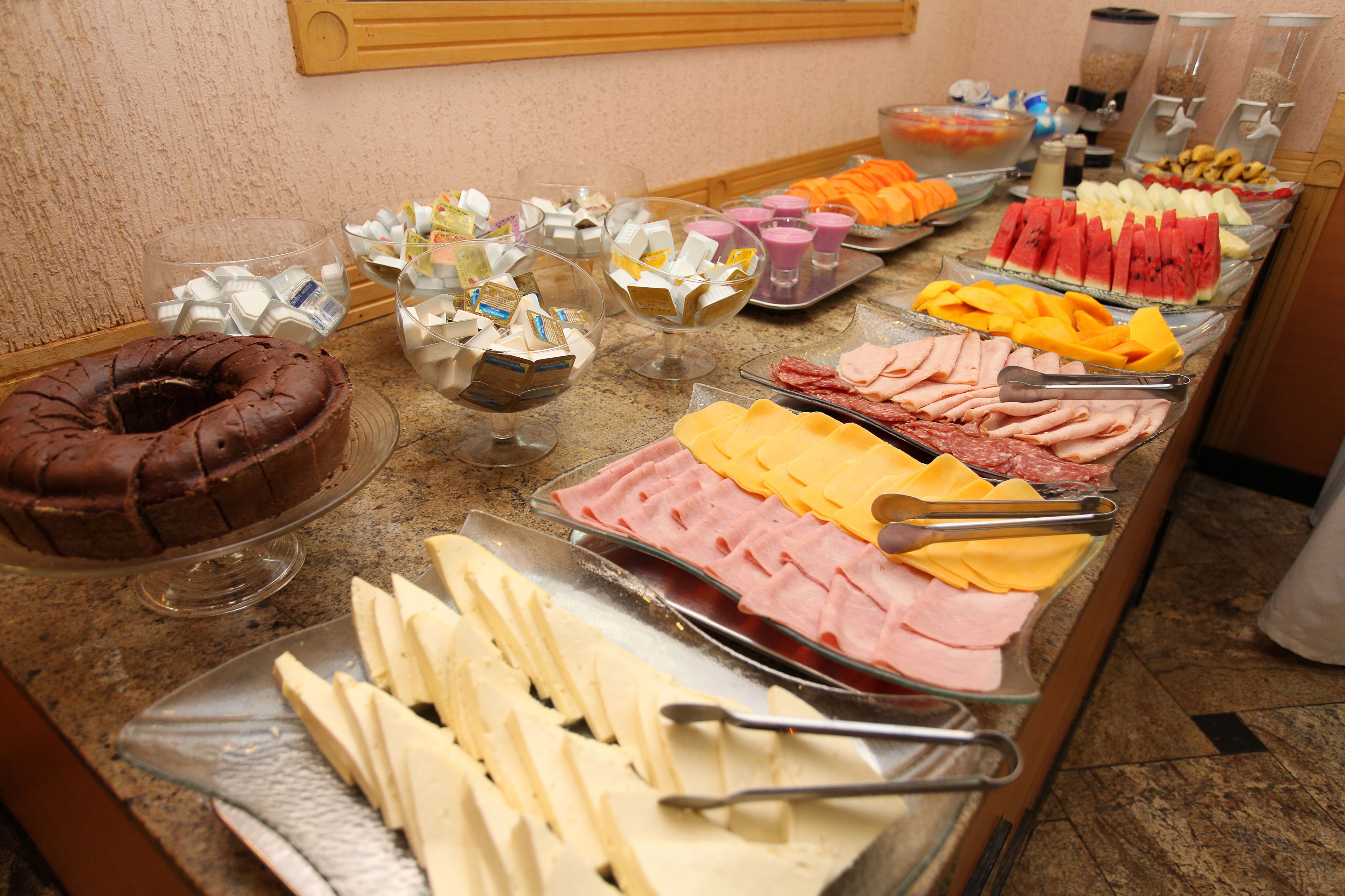 A buffet with various food items including cakes, cheeses, meats, and fruits.