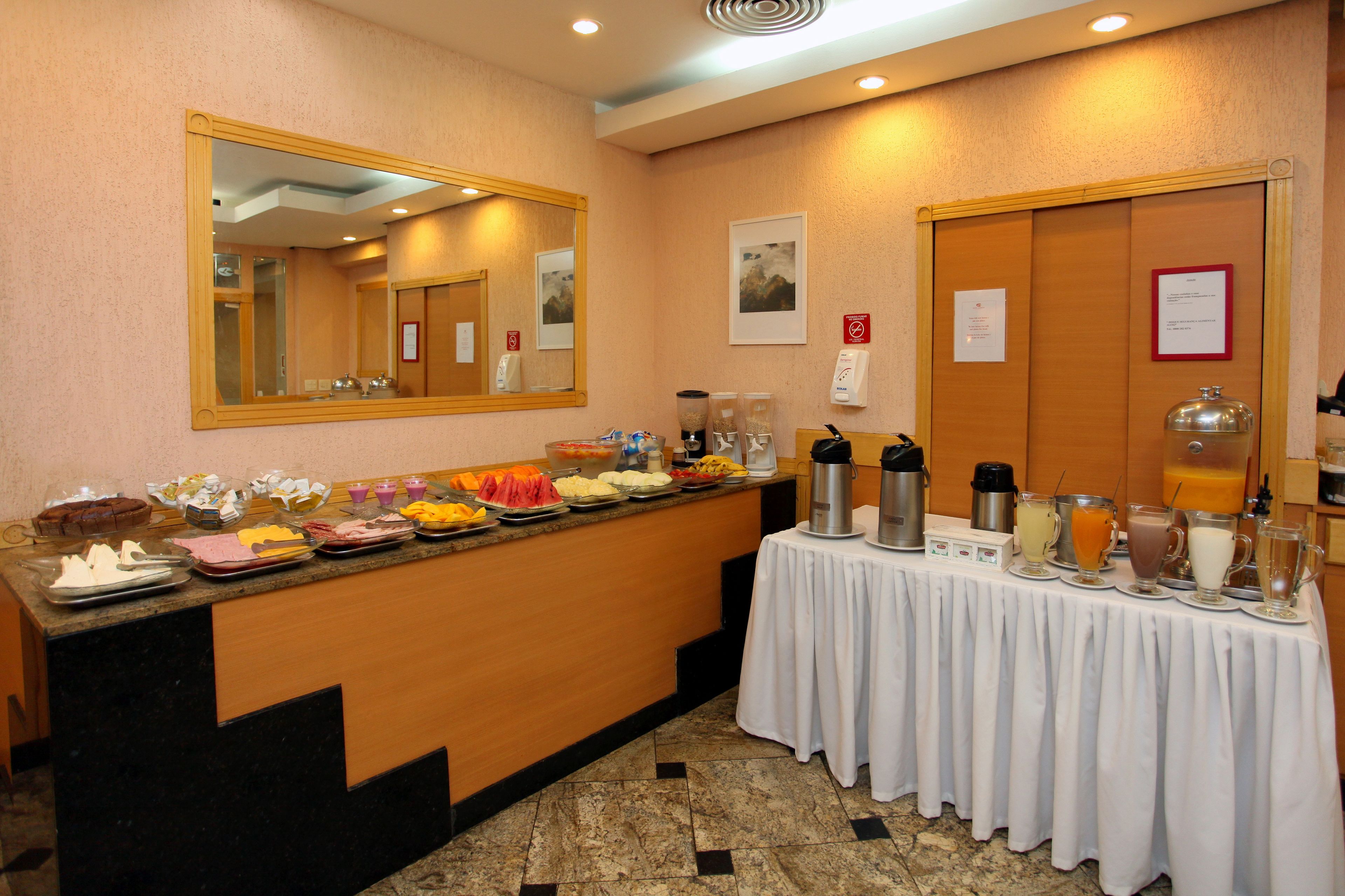 A buffet area with a variety of food items and beverages, a mirror, and a table with a white tablecloth.