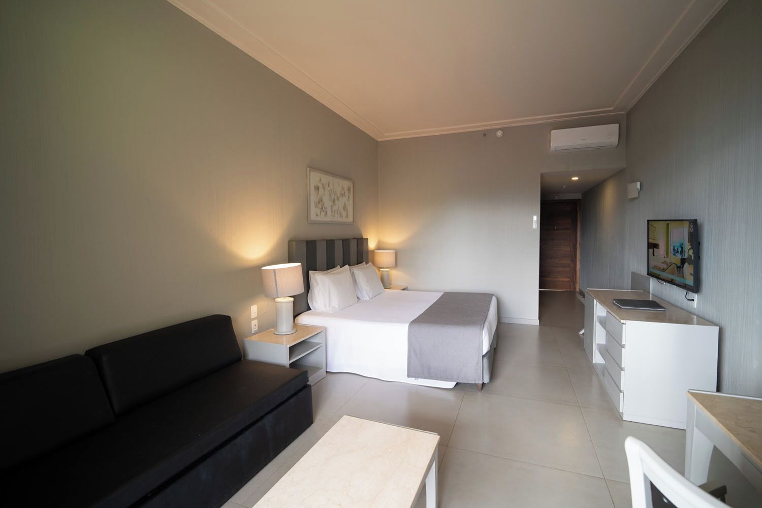 Una habitación de hotel con cama, sofá, escritorio y televisión.