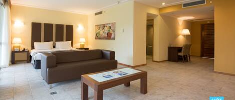 Una habitación de hotel con cama, sofá, mesa de centro y escritorio.