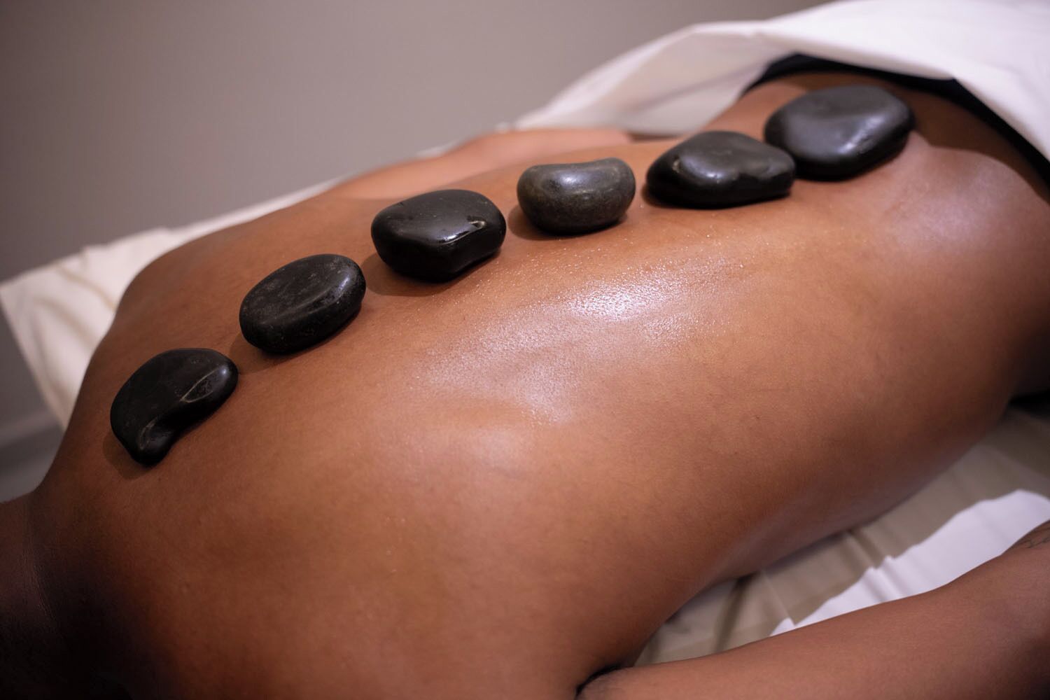 A person receiving a stone massage with seven stones placed on their back.