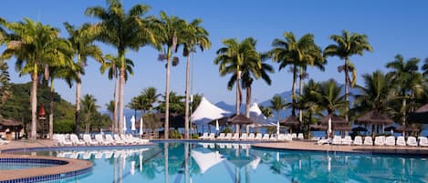 Una piscina al aire libre, sombrillas, sillones reclinables de piscina