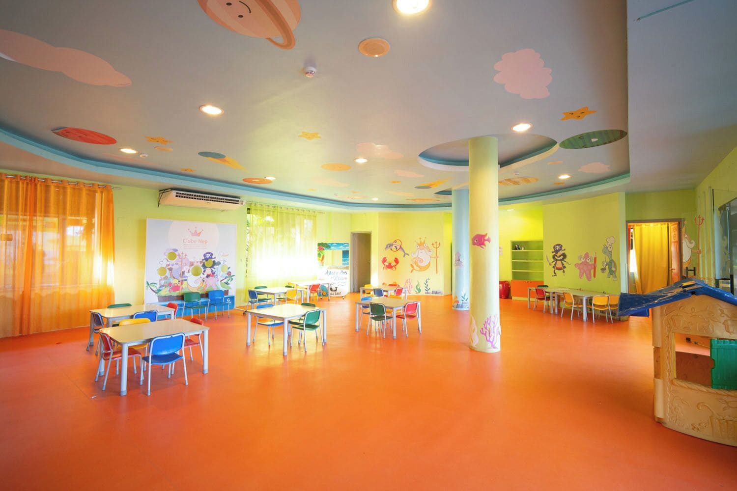 A children's playroom with tables, chairs, and a slide.