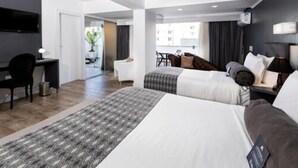 Habitación de hotel con dos camas, un escritorio y una silla.