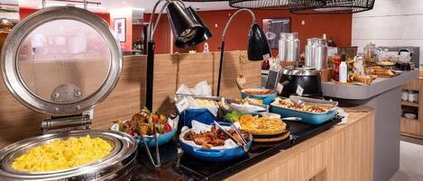 A buffet setup with various food items and a large round griddle.