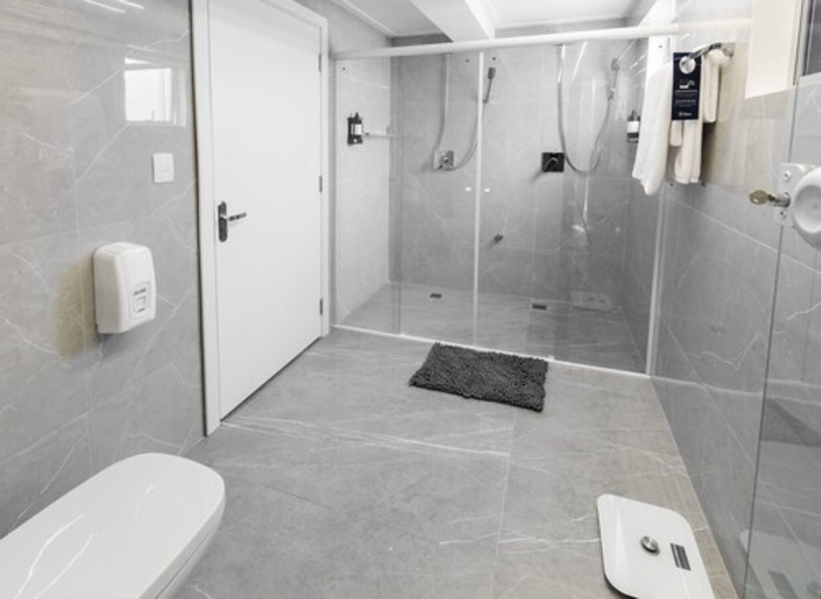 Un baño moderno con ducha envuelta en vidrio, una bañera blanca y un perchero para toallas.