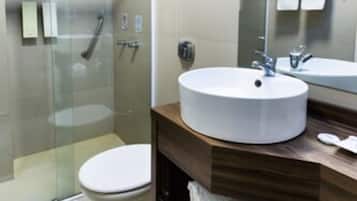 A modern bathroom with a glass-enclosed shower, a round sink, and a wooden vanity with towels.