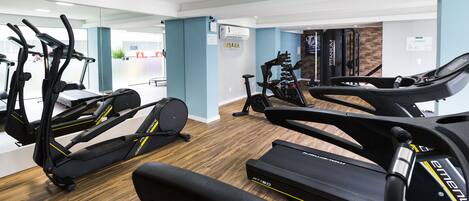 Un gimnasio con cintas de correr, bicicletas estáticas y equipo de ejercicio.