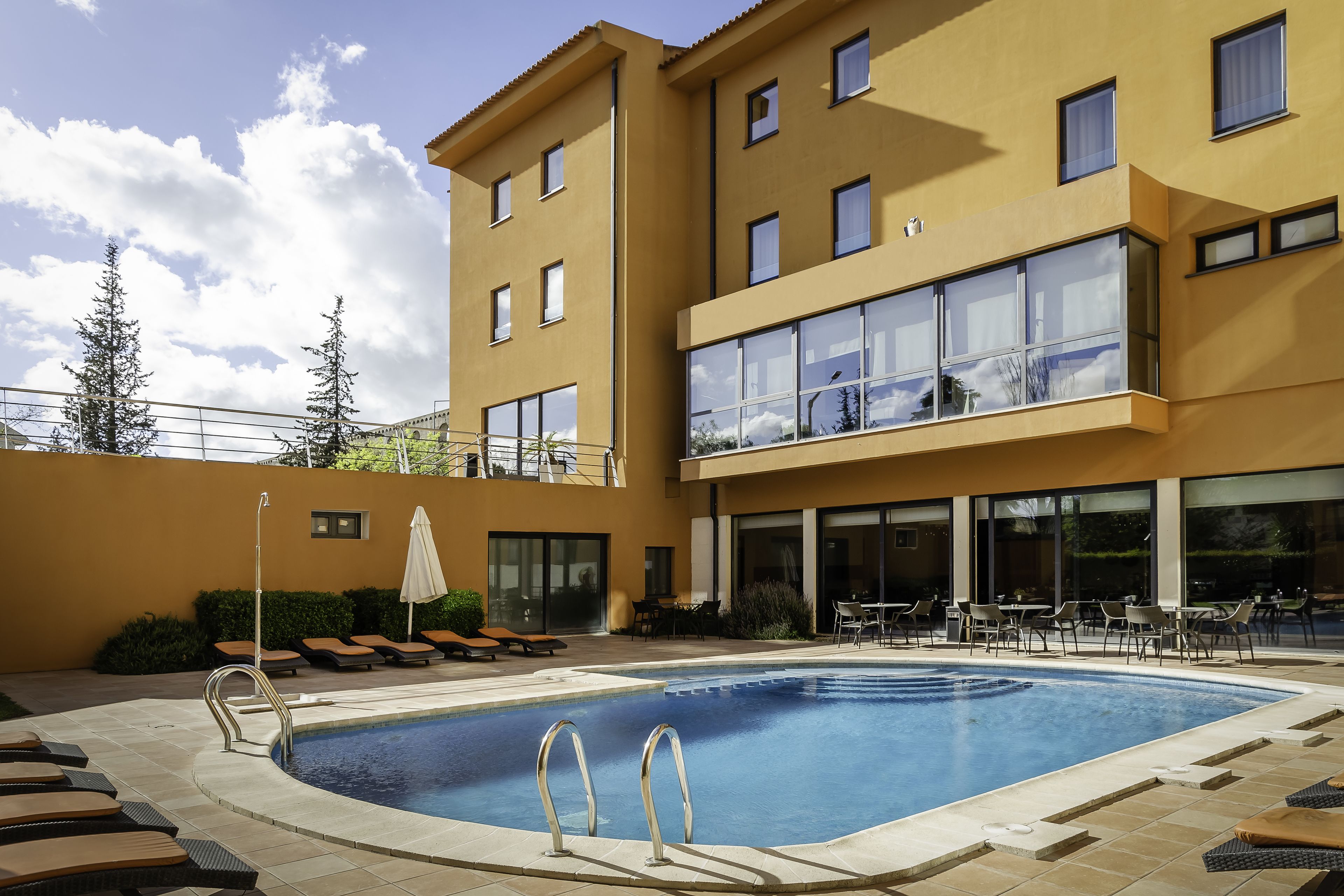 Um hotel moderno com piscina, área de estar externa e varanda com amplas janelas.