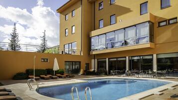 Um hotel moderno com piscina, área de estar externa e varanda com amplas janelas.