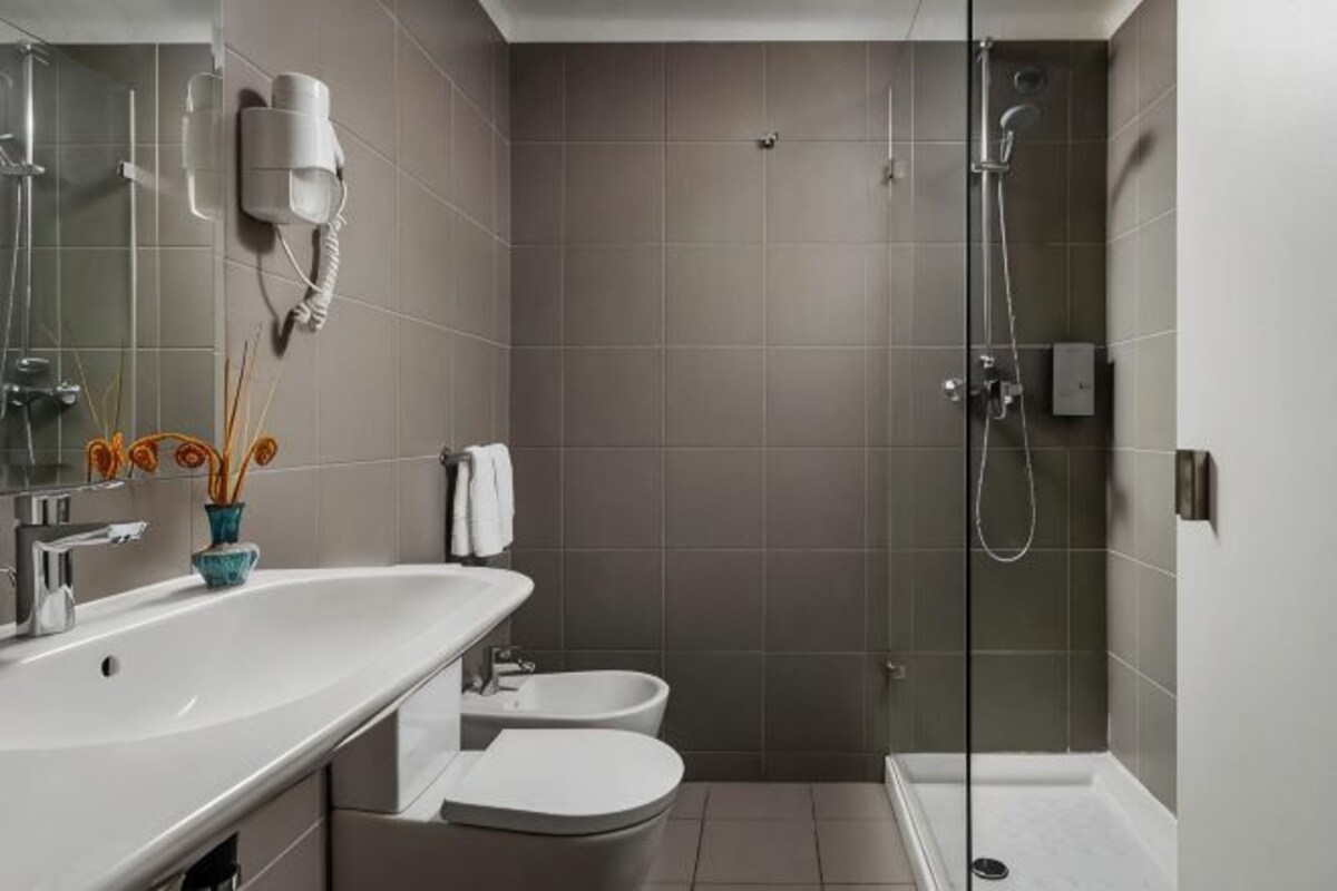 A modern bathroom with a shower, toilet, and sink.
