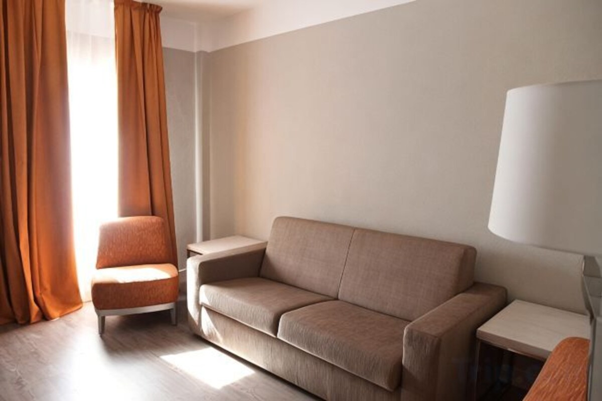 A modern living room with a sofa, armchair, and a lamp.