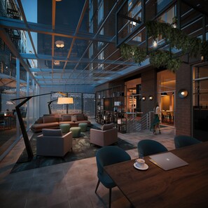 Un vaste espace de détente moderne, doté d’un plafond en verre, de sièges confortables et d’un escalier apparent menant à un niveau supérieur.