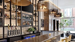 A modern bar area with a marble countertop, multiple bar stools, and a variety of bottles and glasses on shelves.