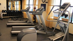 Un gimnasio con cintas de correr, mancuernas y un espejo.