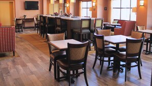 Un restaurante espacioso con varias áreas de comedor, incluyendo cabinas y mesas, y un gran ventanal que proporciona luz natural.