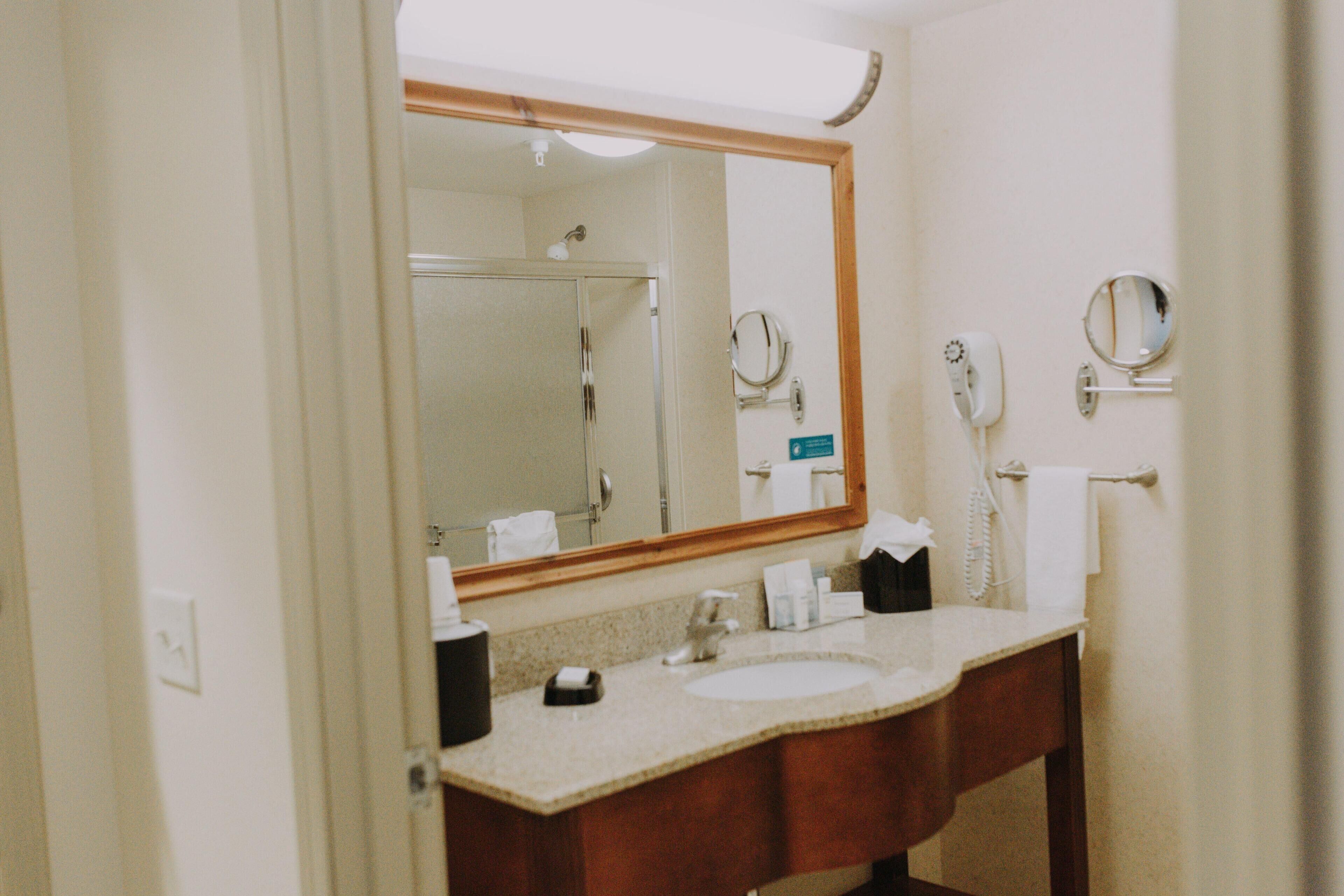 A bathroom with a large mirror, a sink, a towel rack, and a telephone.