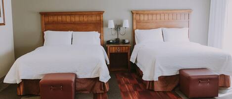 A hotel room with two beds, a nightstand with lamps, and a red carpet.