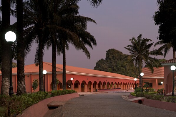 A building with a red facade, arched windows, and a paved entrance area.