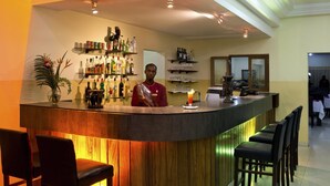Een bar met een toonbank, flessenkasten en barstoelen.