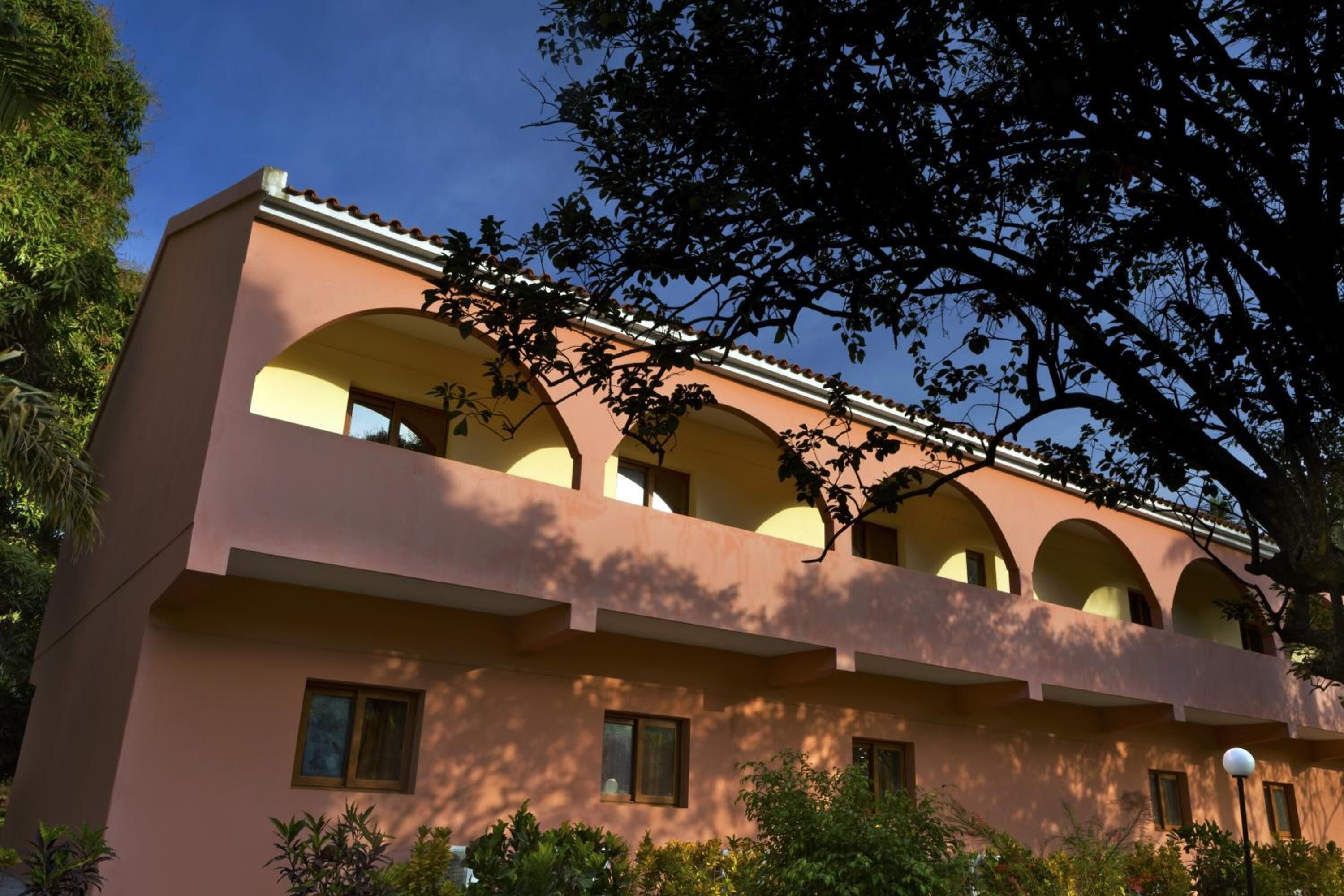 Un edificio con fachada rosa, varios balcones y ventanas arqueadas.