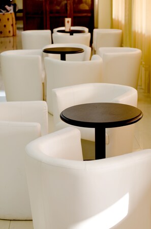 Een zithoek met witte stoelen en ronde tafels, geordend in een cirkelvormig patroon.