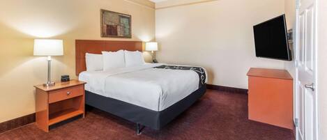A hotel room with a bed, nightstands, a TV, and a painting on the wall.