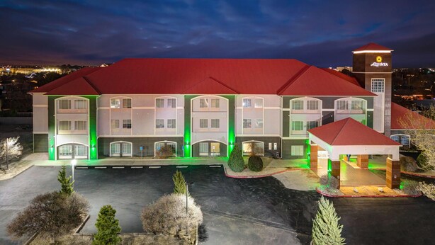 A multi-story hotel with a red roof and green lighting accents. - La Quinta Inn & Suites by Wyndham Hobbs (Hobbs)