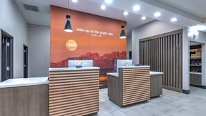 A reception area with two counters, a large wall mural, and a vending machine. - La Quinta Inn & Suites by Wyndham Hobbs (Hobbs)