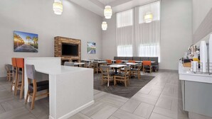 Moderni hotellihuone, jossa on ruokailutila, televisio ja keittiötaso.
