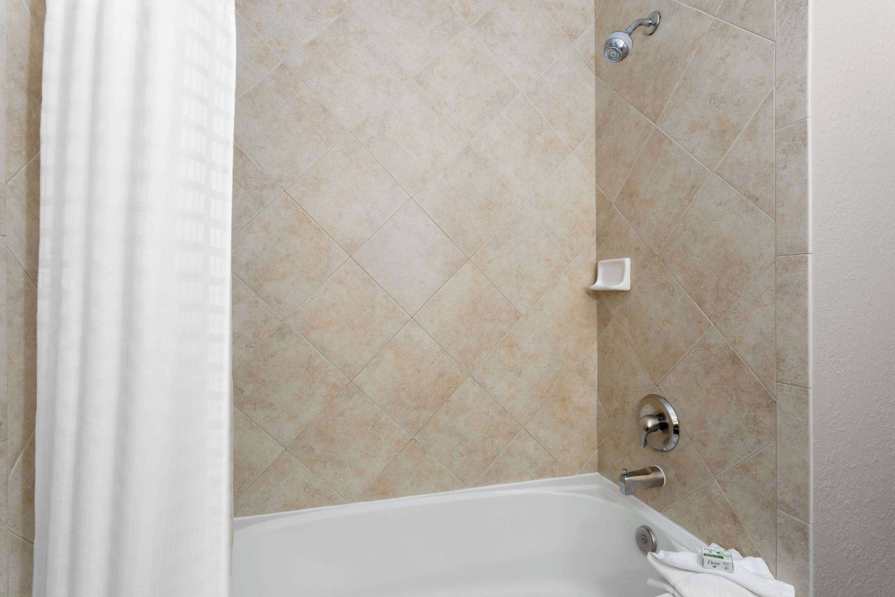 A bathroom with a bathtub, a showerhead, and a soap dish.