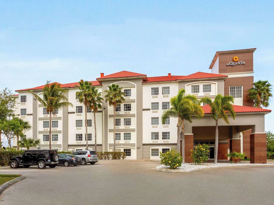 Um hotel de vários andares com telhado vermelho e uma placa com o texto 'La Quinta'.