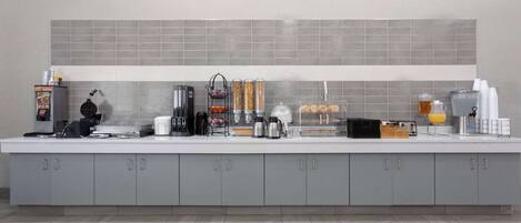 A modern kitchen with grey cabinets, a white countertop, and a grey tiled backsplash.