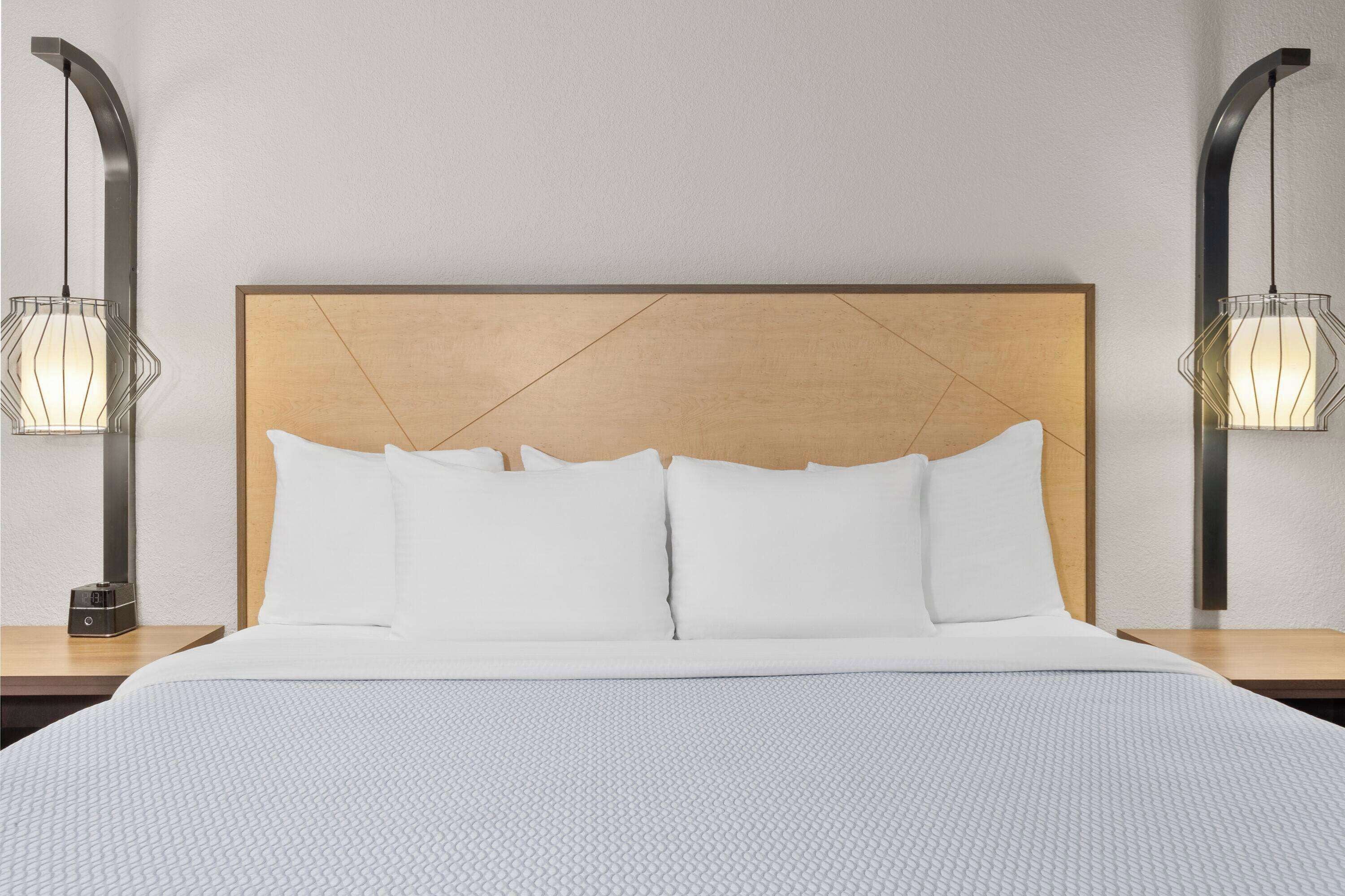 A neatly made bed with a wooden headboard and two bedside lamps.
