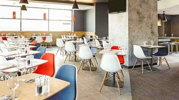 A spacious dining area with multiple tables and chairs, a concrete pillar, and pendant lighting.