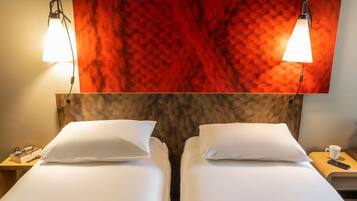 A hotel room with two beds, a red textured wall, and two bedside lamps.