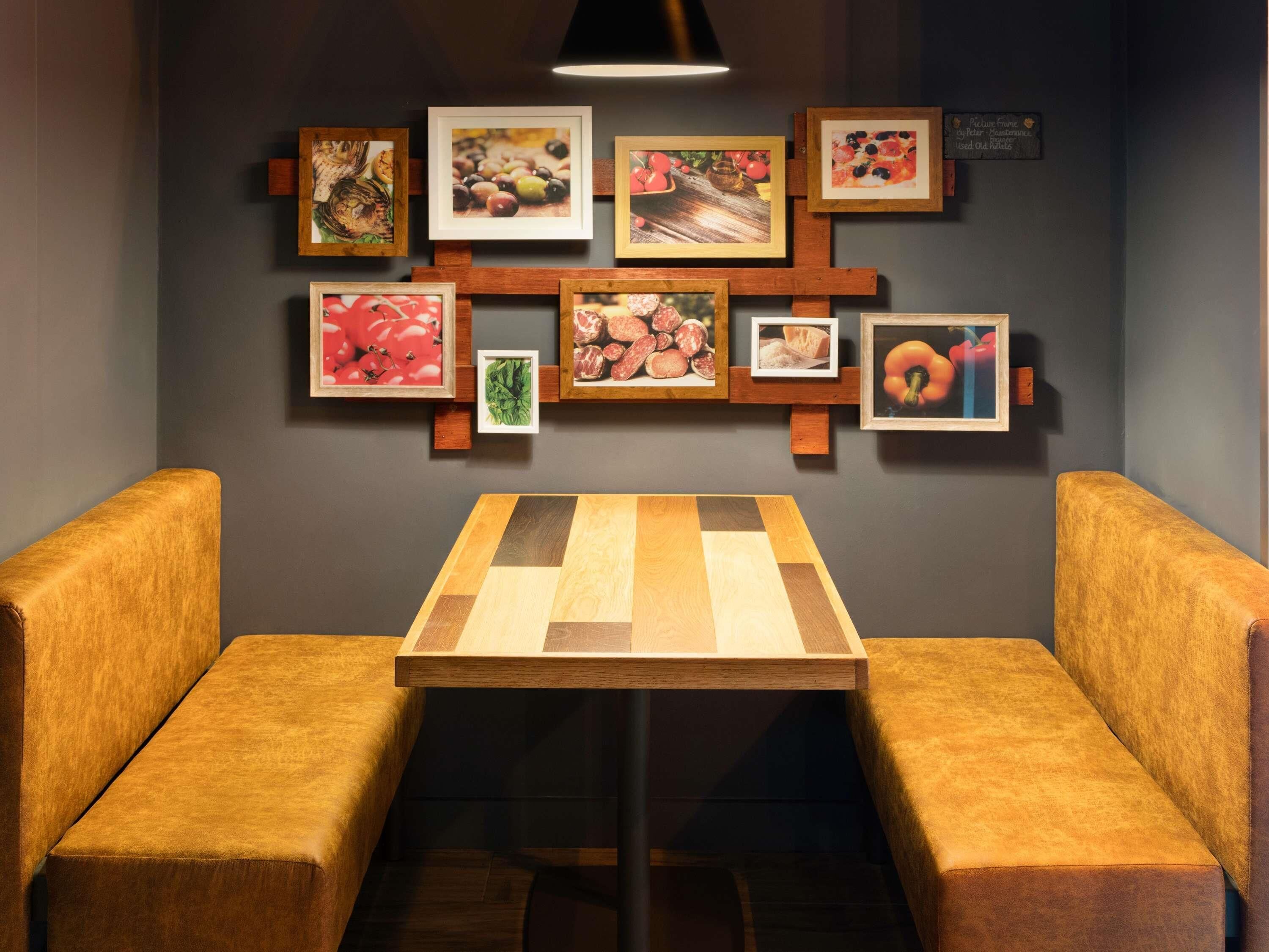 Un espace repas avec une table en bois et deux banquettes rembourrées.