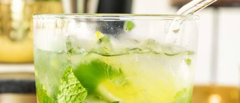Un verre d’une boisson verte, avec des feuilles de menthe et des glaçons.