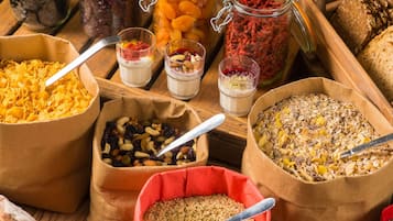 A variety of food items including cereals, nuts, dried fruits, and grains displayed in paper bags and jars.