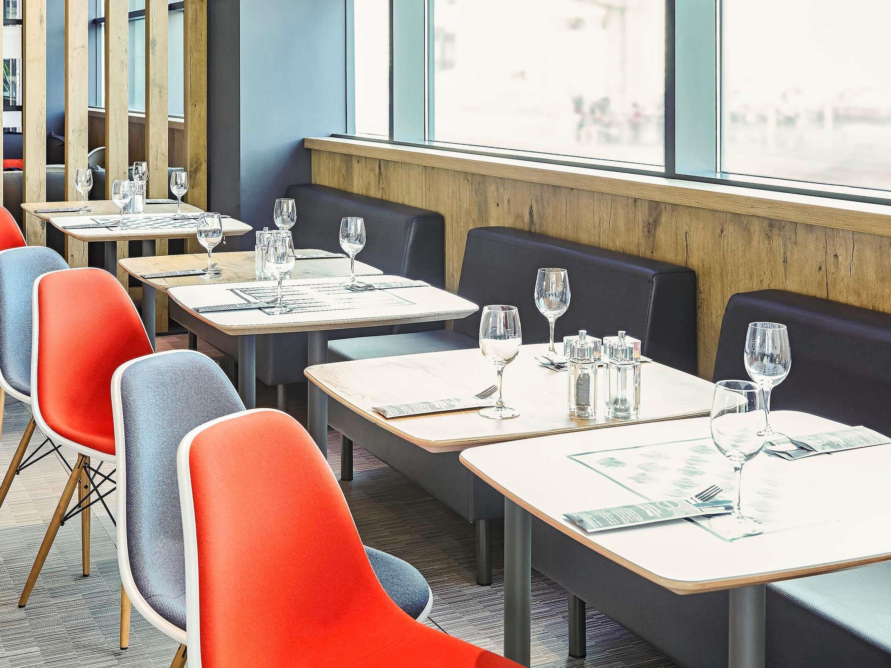 A restaurant with multiple tables and chairs, each set with a menu, glasses, and cutlery.