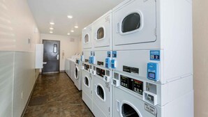 A laundry facility with multiple washing machines and dryers, each with a control panel and a QR code. - Extended Stay America Select Suites - Phoenix - Peoria - Sun City (Peoria)