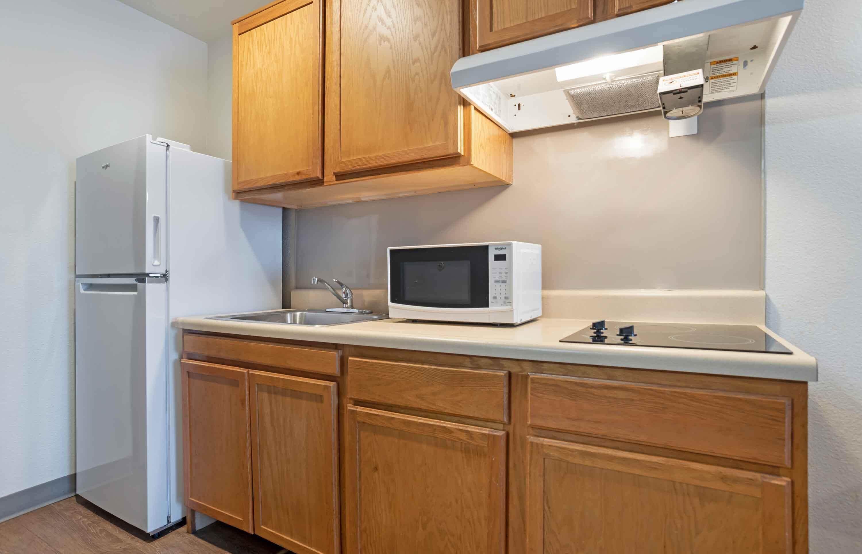 A kitchen with wooden cabinets, a white refrigerator, a microwave, and a sink.