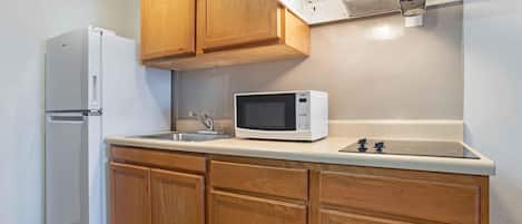 A kitchen with wooden cabinets, a white refrigerator, a microwave, and a sink.
