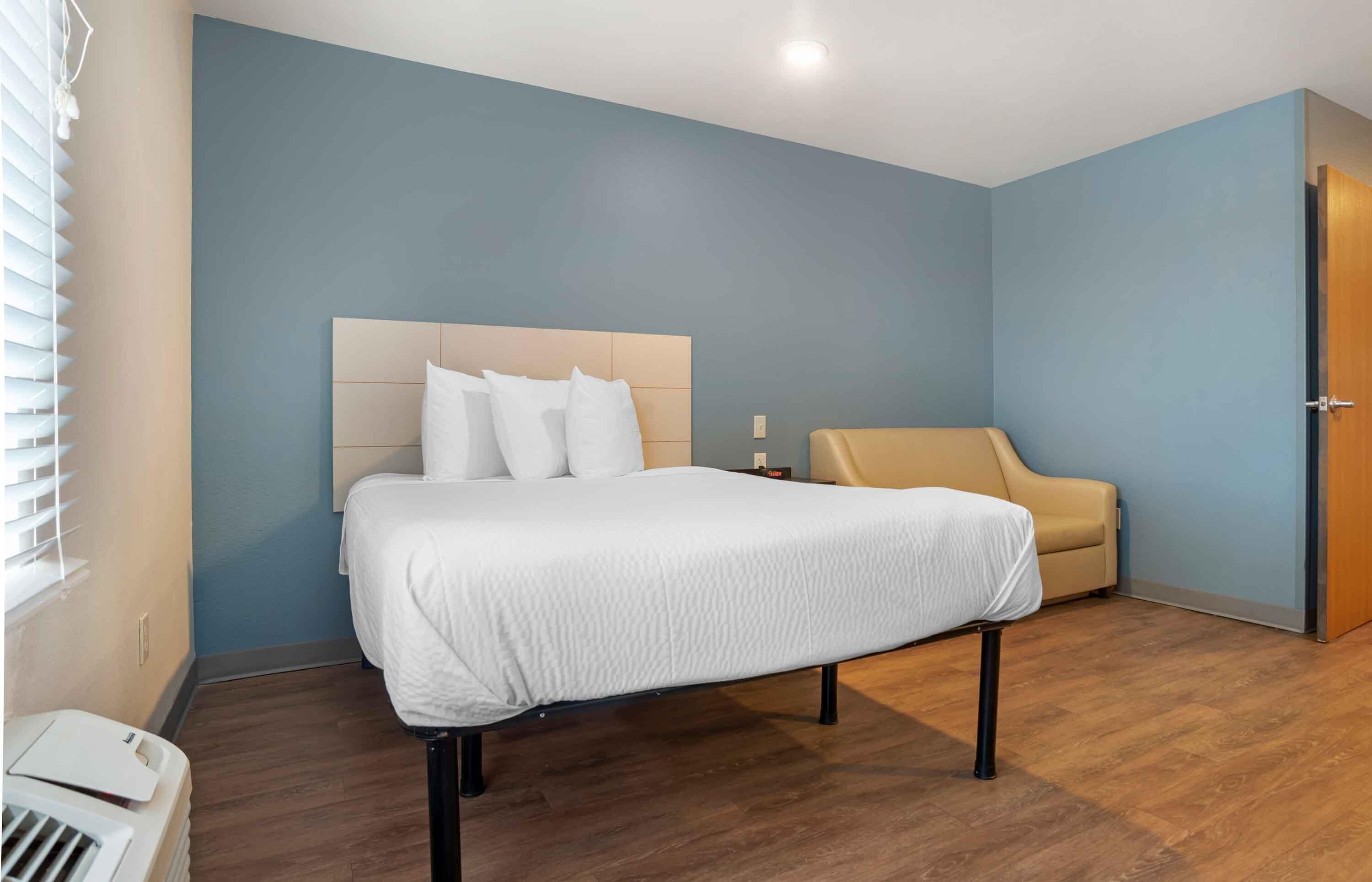 Une chambre à coucher avec un lit, une table de chevet, une chaise et une porte.