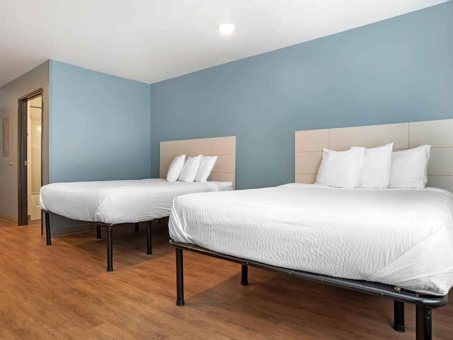 Habitación de hotel con dos camas, suelo de madera y paredes azul claro.