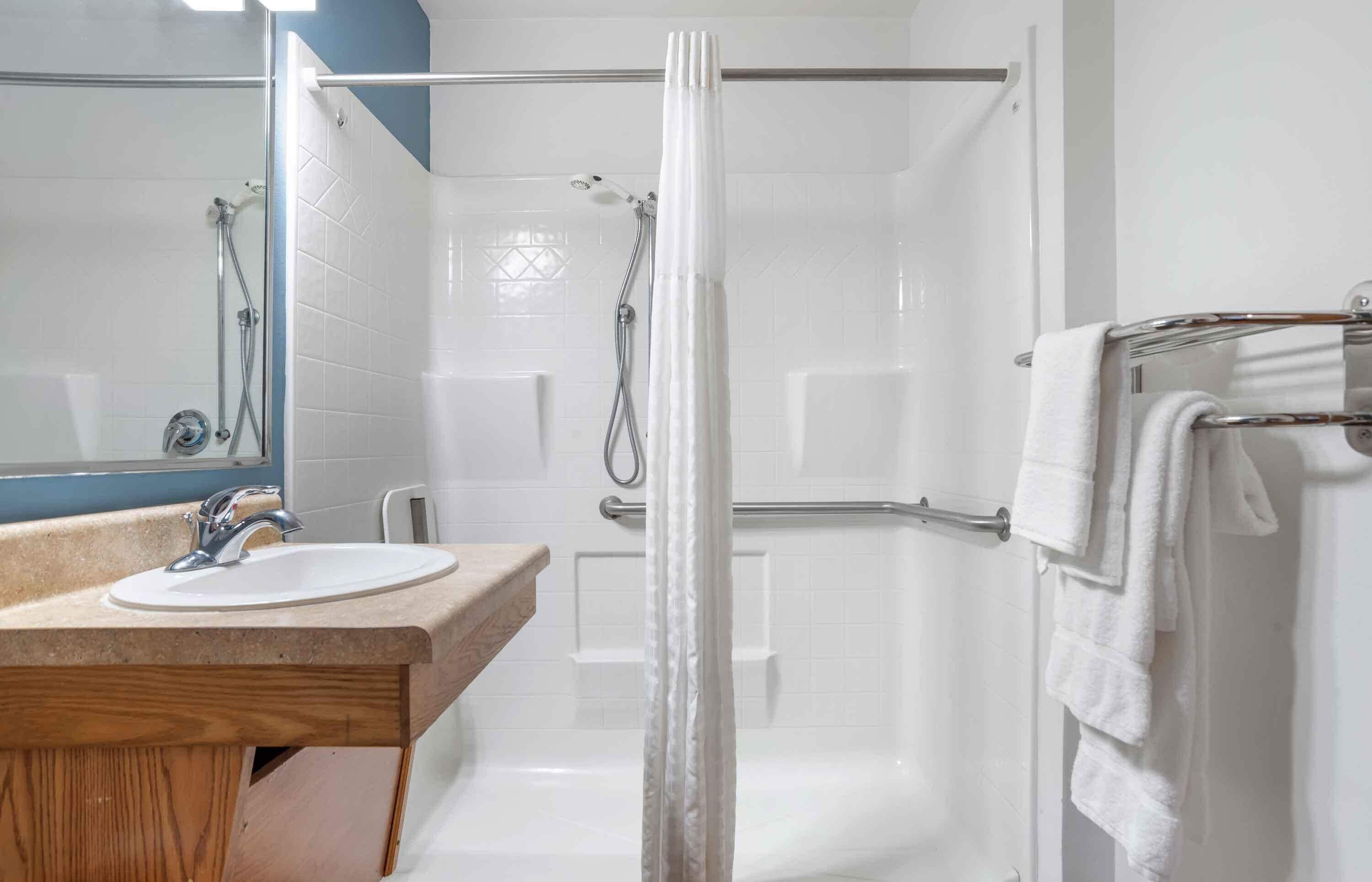 Un baño moderno con cabina de ducha de vidrio, un lavabo blanco y un perchero para toallas.