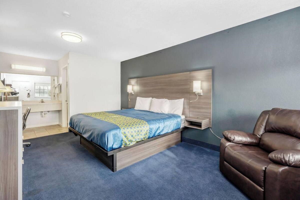 A hotel room with a bed, a desk, a chair, and a bathroom.